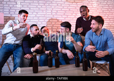 Group Of Cheerful Young Men Toasting With Tequila At A Nightclub Stock Photo