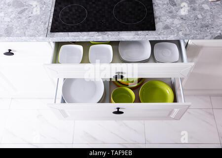 Set Of Different Clean Plates Inside The Opened Drawers In Kitchen Stock Photo