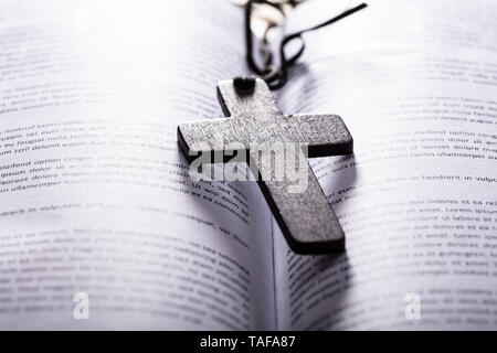 Close-up Of Opened Holy Bible With Wooden Cross Stock Photo