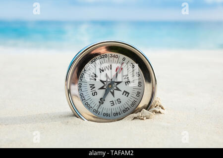 Close-up Of Golden Compass Buried In The Sandy Beach Stock Photo