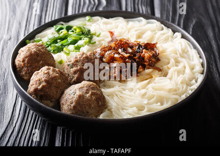 Indonesian traditional food bakso meatballs with noodles, onions, greens and broth close-up on a plate on the table. horizontal Stock Photo