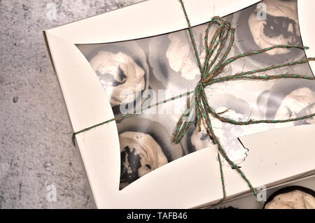 beautiful chocolate cakes covered with cream in a white box tied with a rope on a concrete background Stock Photo