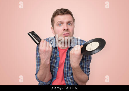 Man with tape cassette and old retro vinyl confused and puzzled Stock Photo