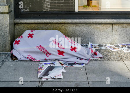 Homeless person sleeping under red cross blanket, Vancouver, British Columbia, Canada Stock Photo