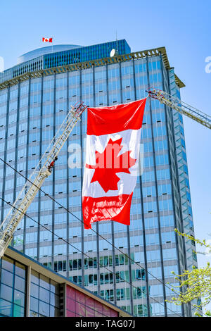 Canadian flag helsd aloft by 2 Fire truck ladders in salute to firefighter who died on duty, Vancouver, British Columbia, Canada Stock Photo