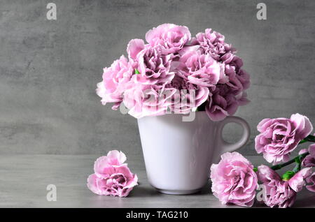 Pink carnation flowers in cup on grey background. Holiday concept. Stock Photo