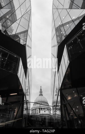 A view of St Paul's Cathedral roof dome looking up an between two modern glass buildings One New Change shopping contrast