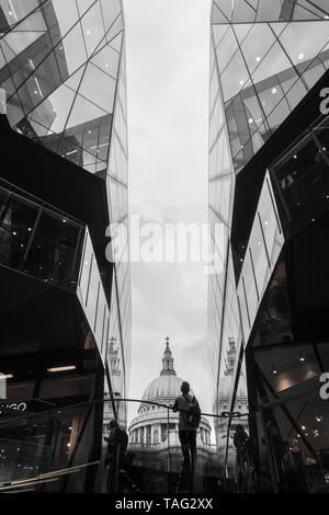 A view of St Paul's Cathedral roof dome looking up an between two modern glass buildings One New Change shopping person