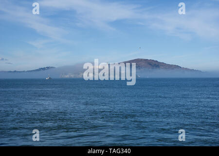 SAN FRANCISCO, CALIFORNIA, UNITED STATES - NOV 25th, 2018: Alcatraz prison in fog panorama during a sunny day in November as seen from pier 39 Stock Photo