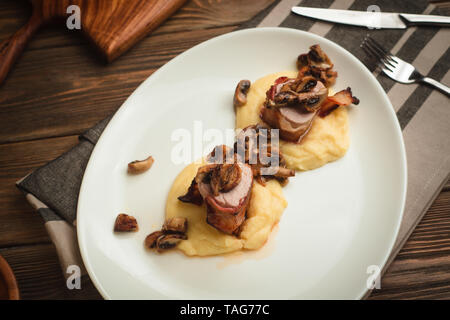 Pork neck with mushrooms and mashed potatoes. Cafe menu on a wooden background in warm colors with copy space. Stock Photo