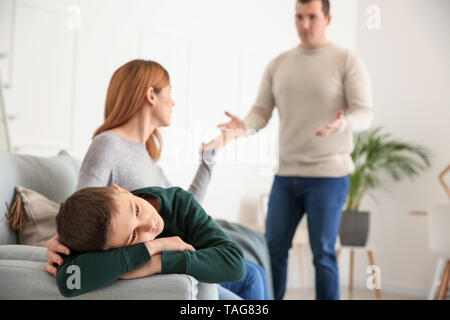 Sad little boy with his quarreling parents at home Stock Photo