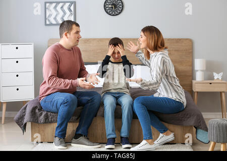 Sad little boy covering ears while his parents arguing at home Stock Photo
