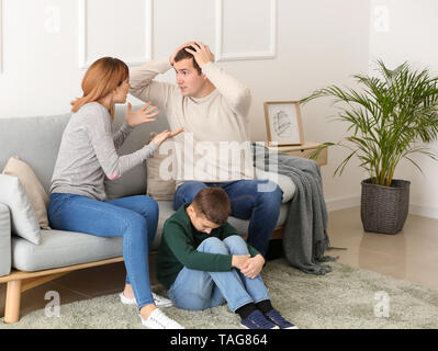 Sad little boy with his quarreling parents at home Stock Photo