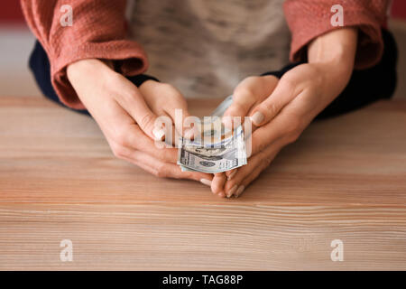 Woman with his son holding dollar banknotes on wooden table. Concept of child support Stock Photo