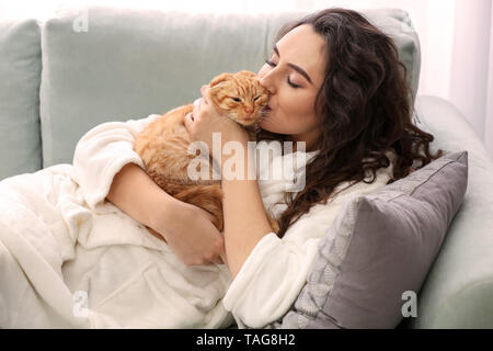 Young woman kissing cute funny cat at home Stock Photo