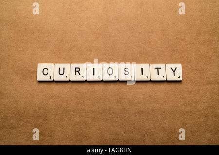 LONDON, UK - May 24 2019: The word CURIOSITY, spelt with wooden letter tiles over a brown textured background Stock Photo