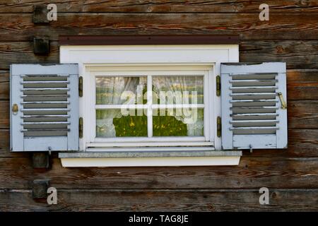 small white painted window with blue shutters in an old wooden house Stock Photo