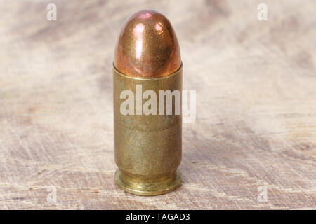 .45 ACP (Automatic Colt Pistol), or .45 Auto (11.43x23mm) a handgun cartridge designed by John Browning in 1905 on wooden background Stock Photo