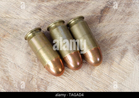 .45 ACP (Automatic Colt Pistol), or .45 Auto (11.43x23mm) a handgun cartridges designed by John Browning in 1905 on wooden background Stock Photo