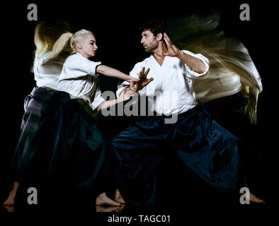 two budokas fighters man and woman practicing Aikido studio shot isolated on black background Stock Photo