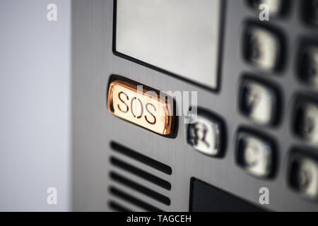 button SOS. The SOS button on the device panel, intercom. Help call button on the screen of the device in gray metal color. Stock Photo