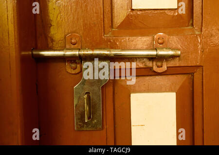 Closeup front view exterior rusty rough old brown wooden door handle of iron metal frame with in grungy style and good texture of a full closed door o Stock Photo