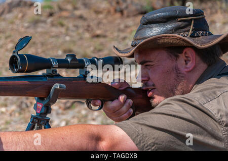 Close-up of the face of a professional hunter taking aim at a target on a game farm in Namibia. Stock Photo