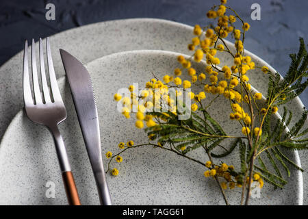 Festive table setting with mimosa flowers for easter holiday dinner Stock Photo