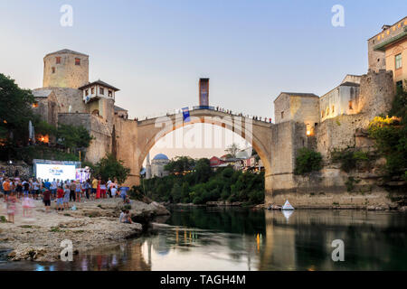 MOSTAR, BOSNIA AND HERZEGOVINA - AUGUST 13, 2015: Dusk photo of Tourist and locals walking near Old bridge in Mostar while there are preparation for R Stock Photo