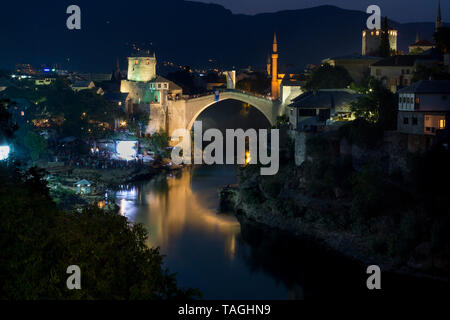 MOSTAR, BOSNIA AND HERZEGOVINA - AUGUST 13, 2015: Night photo of Tourist and locals walking near Old bridge in Mostar. Stock Photo