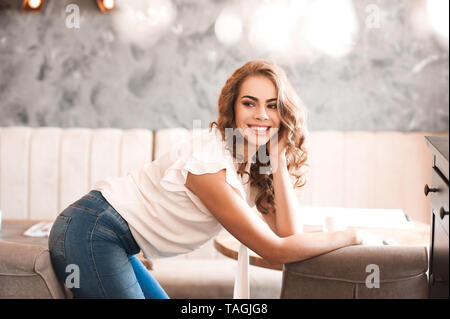 smiling beautiful woman 20 24 year old with curly hair posing in cafe looking at camera 20s tagjg8