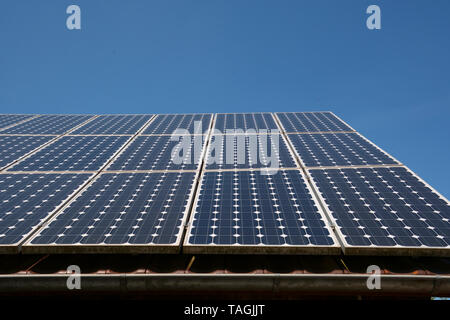 solar panel soak up the blue sky sun, modern solar cells or photovoltaic on the roof of an old woodshed with new gutter in front of azure sky Stock Photo