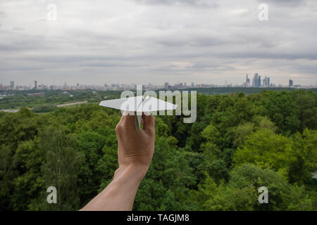 Human hand holding paper plane against Moscow cityscape Stock Photo