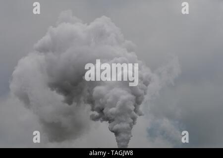 impressing cloud of smoke joining the rain clouds in the sky Stock Photo