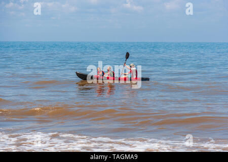 father and two young children kayaking in the sea Stock Photo