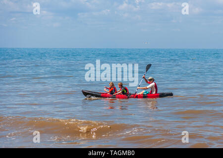 father and two young children kayaking in the sea Stock Photo