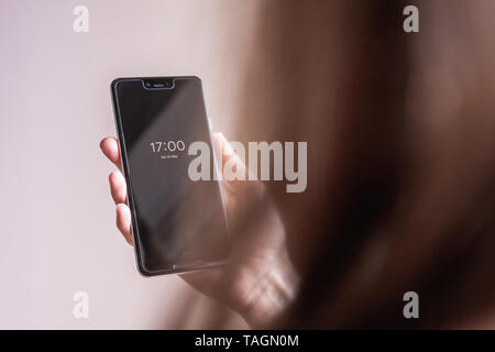 Woman holding Google Pixel 3 XL in front of plain background showing the time Stock Photo