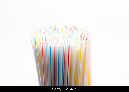 A close-up shot with selective focus of a bunch of unused colored bendy plastic straws set on a plain white background. Stock Photo