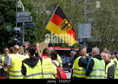 Wiesbaden, Germany. 25th May 2019. A protester waves a German flag. Under 100 right wing protesters marched with yellow vests through Wiesbaden, to protest against the German government. They were confronted by small but loud counter protest. Stock Photo