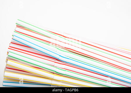 A close-up shot with selective focus of a bunch of unused colored bendy plastic straws set on a plain white background. Stock Photo