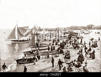 A late 19th Century view of yachts on the beach, and about to part in the August Regatta in Great Yarmouth, aka Yarmouth, a seaside town in Norfolk, England. It has been a seaside resort since 1760, providing also a gateway from the Norfolk Broads to the North Sea as well as a longstanding fishing port. As a tourist centre, Yarmouth rose to prominence when a railway built in 1844 gave visitors easier and cheaper access and triggered an influx of settlers.