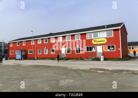 Tourists exploring in the village of Paamiut on the west coast of Greenland.  The Cafe Paamiut sign is on the ground floor of a two story building. Stock Photo