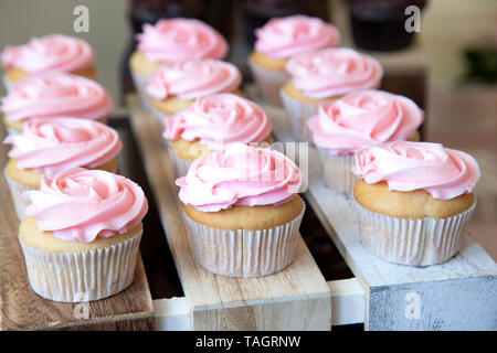 Gorgeous pink frosting on top of beautiful white vanilla cupcakes at a party or celebration Stock Photo