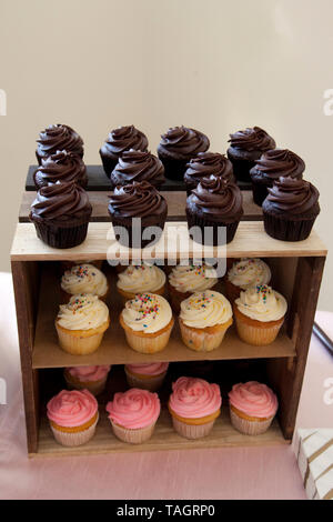 Chocolate, strawberry and vanilla cupcakes on a wooden table display Stock Photo