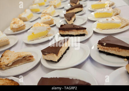Cheesecake, lemon and apple pies ready to be served on single plates as slices Stock Photo