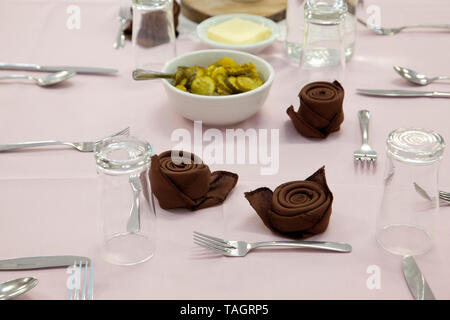 A table set with glasses, pickles, napkins, and utensils Stock Photo
