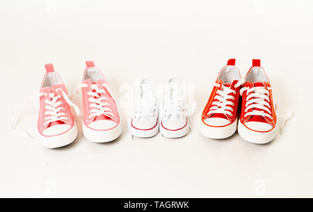 Conceptual image of gumshoes sneakers of two mothers and son daughter isolated on white background copy space in modern family togetherness Parenting  Stock Photo