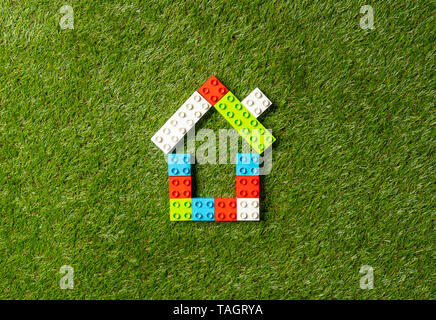 Conceptual picture of children toy blocks house on green grass field top view and copy space in Property investment Real estate Saving and buying home Stock Photo