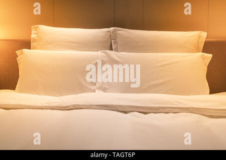 White sheets king size bed with double pillows and warm light Stock Photo