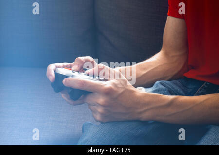 Young man playing video games at night using a gamepad. Closeup. Stock Photo